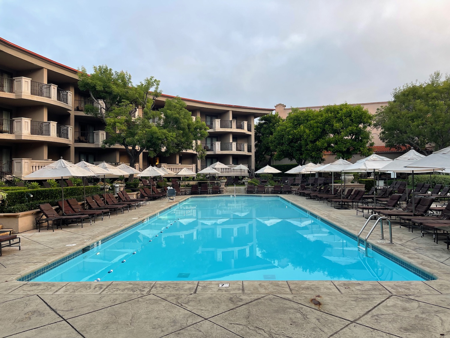 a pool with chairs and umbrellas in front of a building