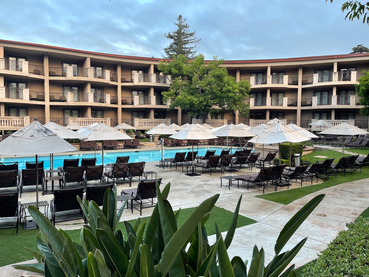 a pool with umbrellas and chairs in front of a building