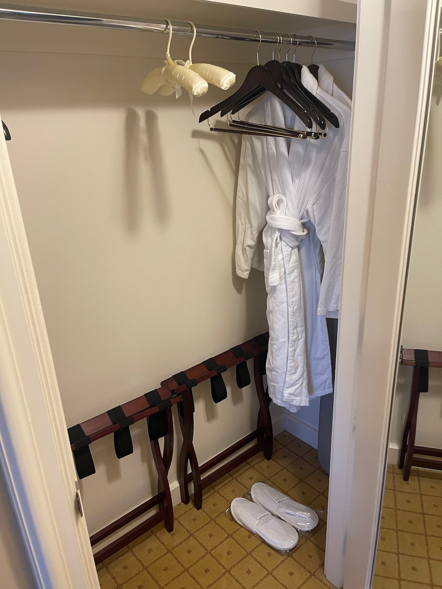 a closet with white bathrobes and white shoes