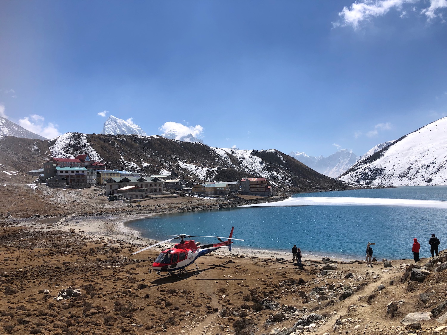 a helicopter on a beach with a body of water and mountains in the background