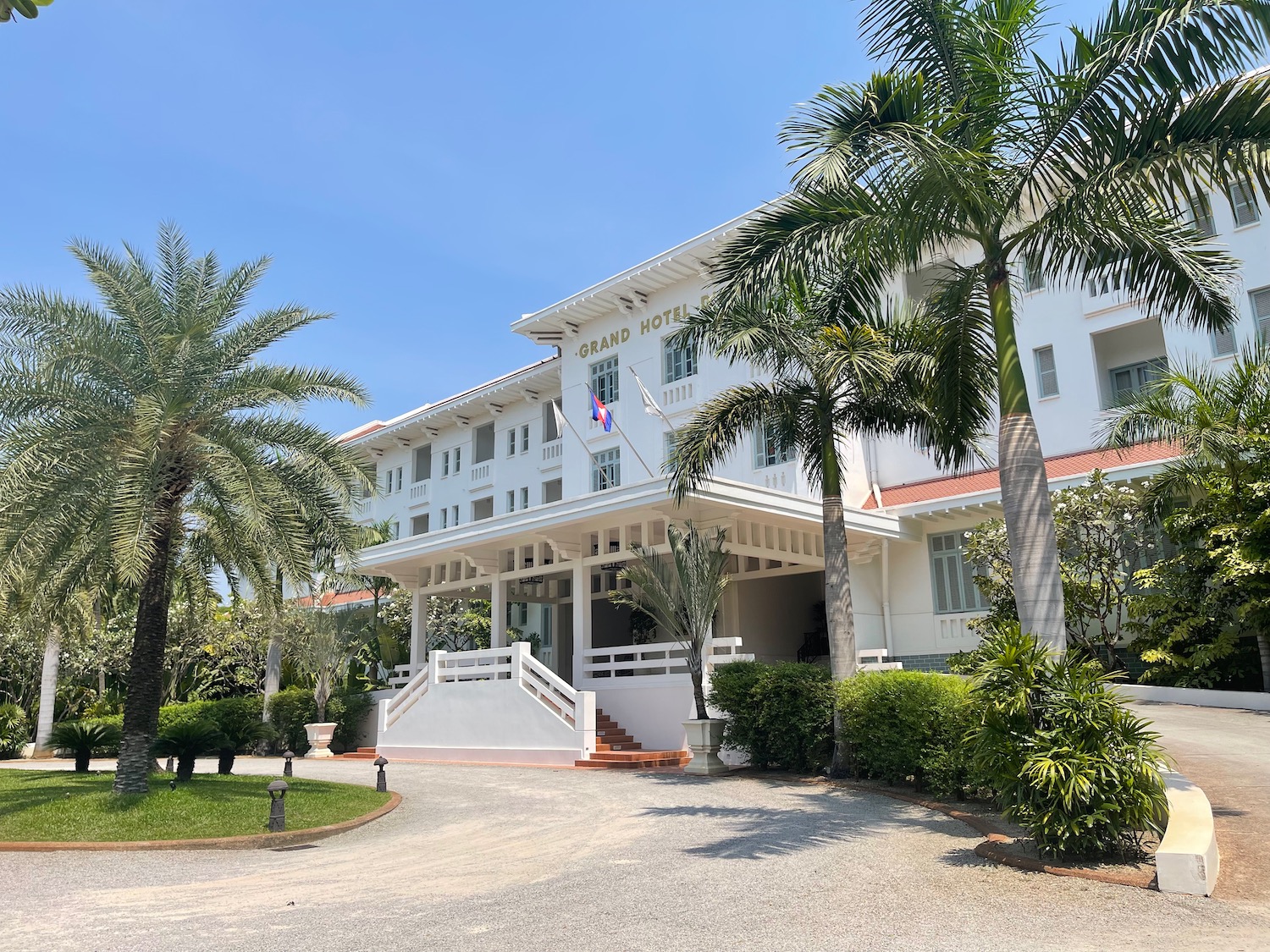 a white building with palm trees and a driveway