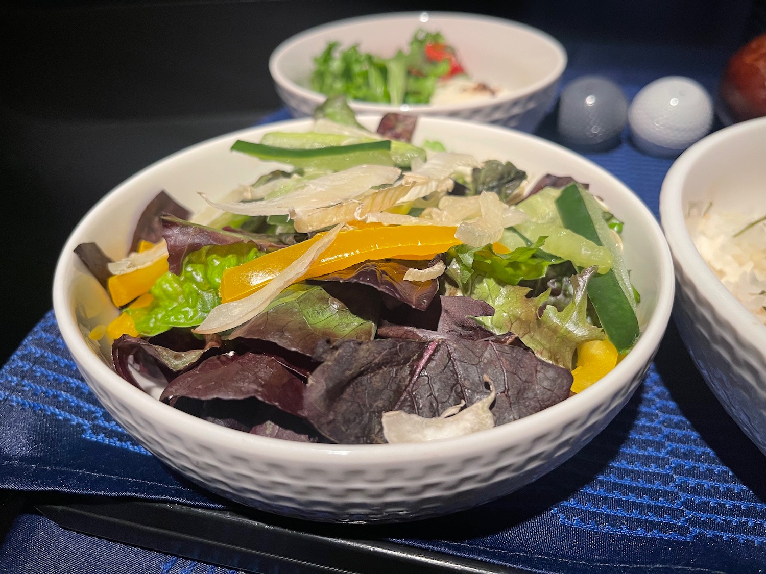 a bowl of salad on a blue place mat