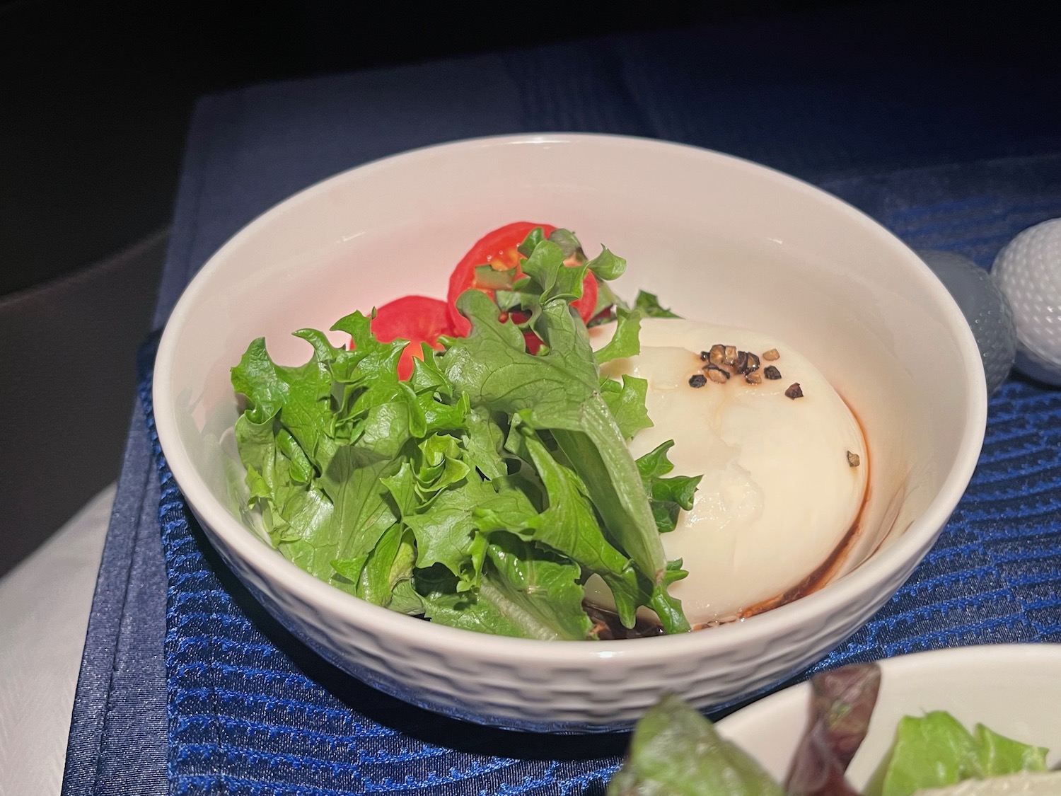 a bowl of salad with a white object and tomatoes