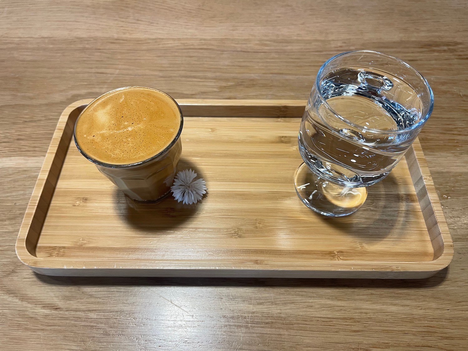 a glass of water and a drink on a wooden tray