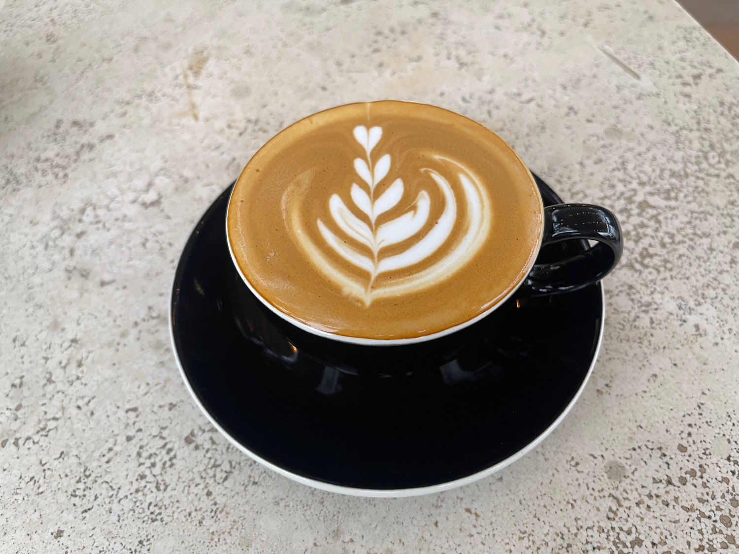 a cup of coffee with a leaf design in the foam