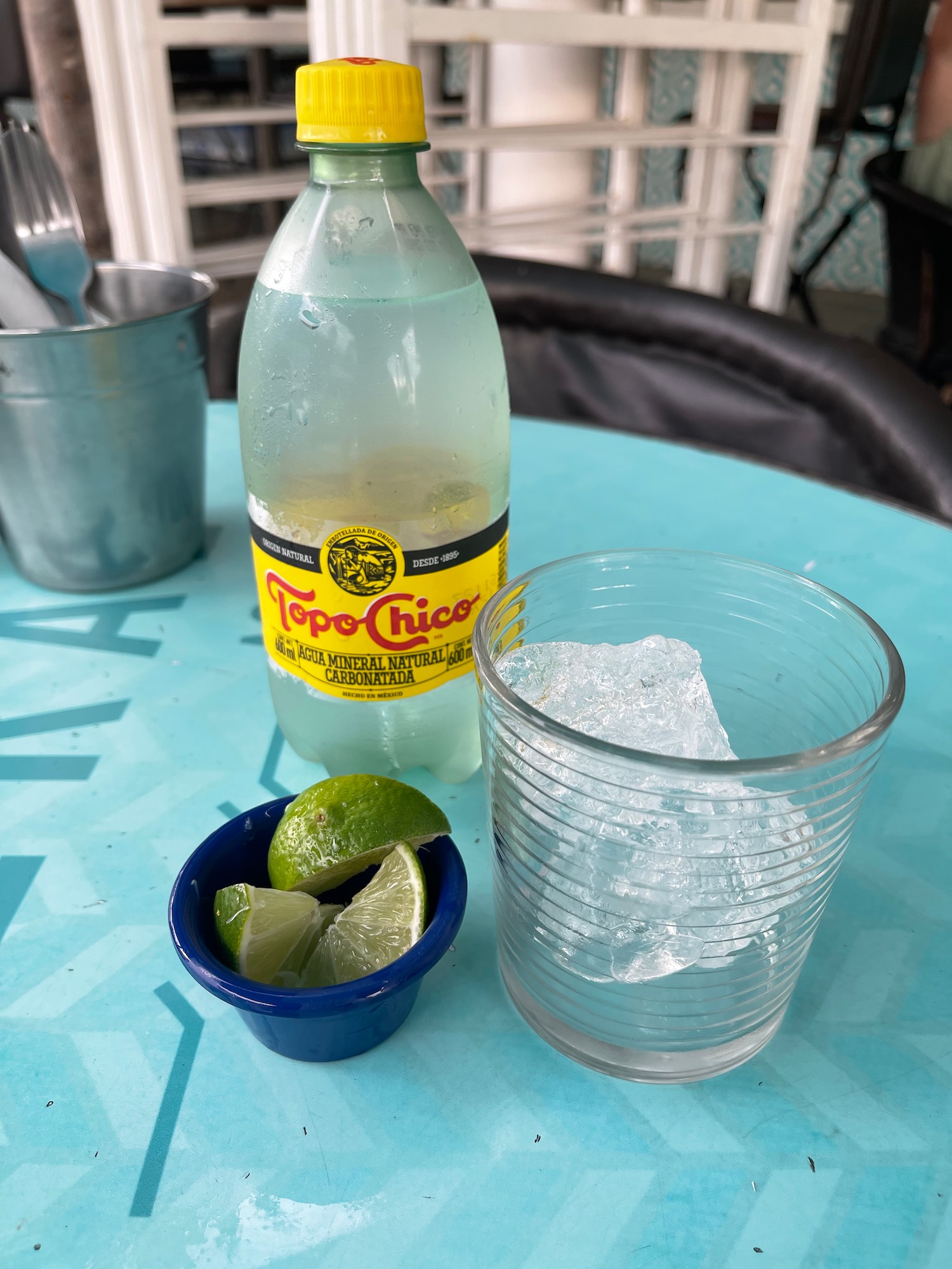 a bottle of soda and a glass of ice and limes