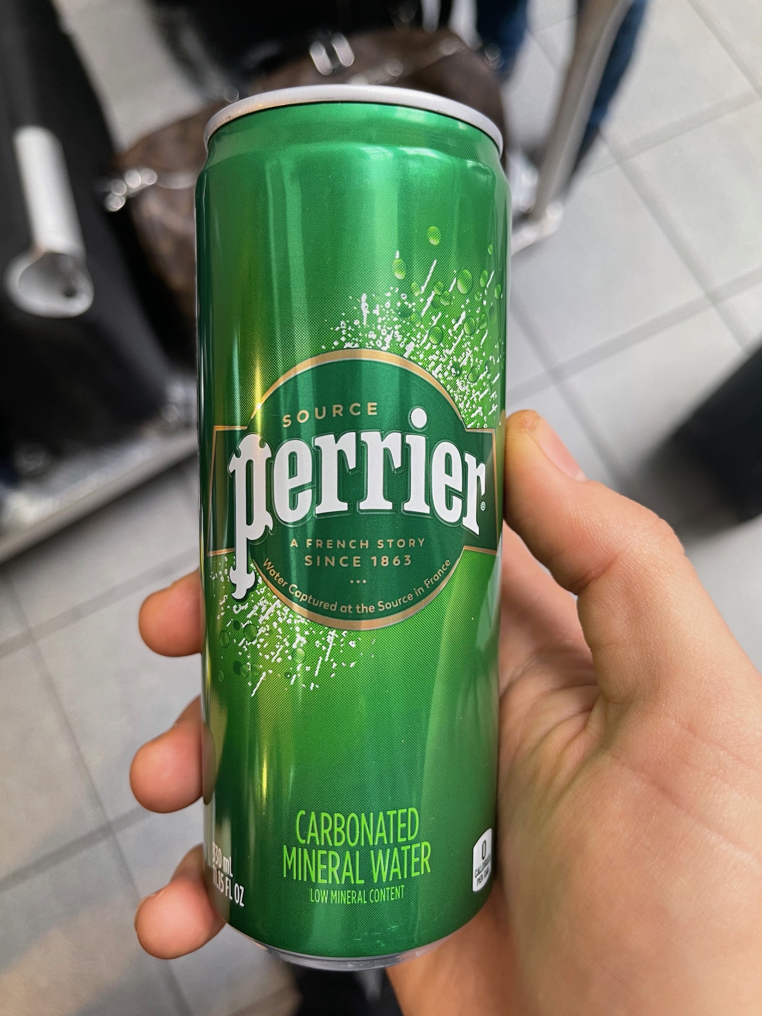 a hand holding a green can of mineral water