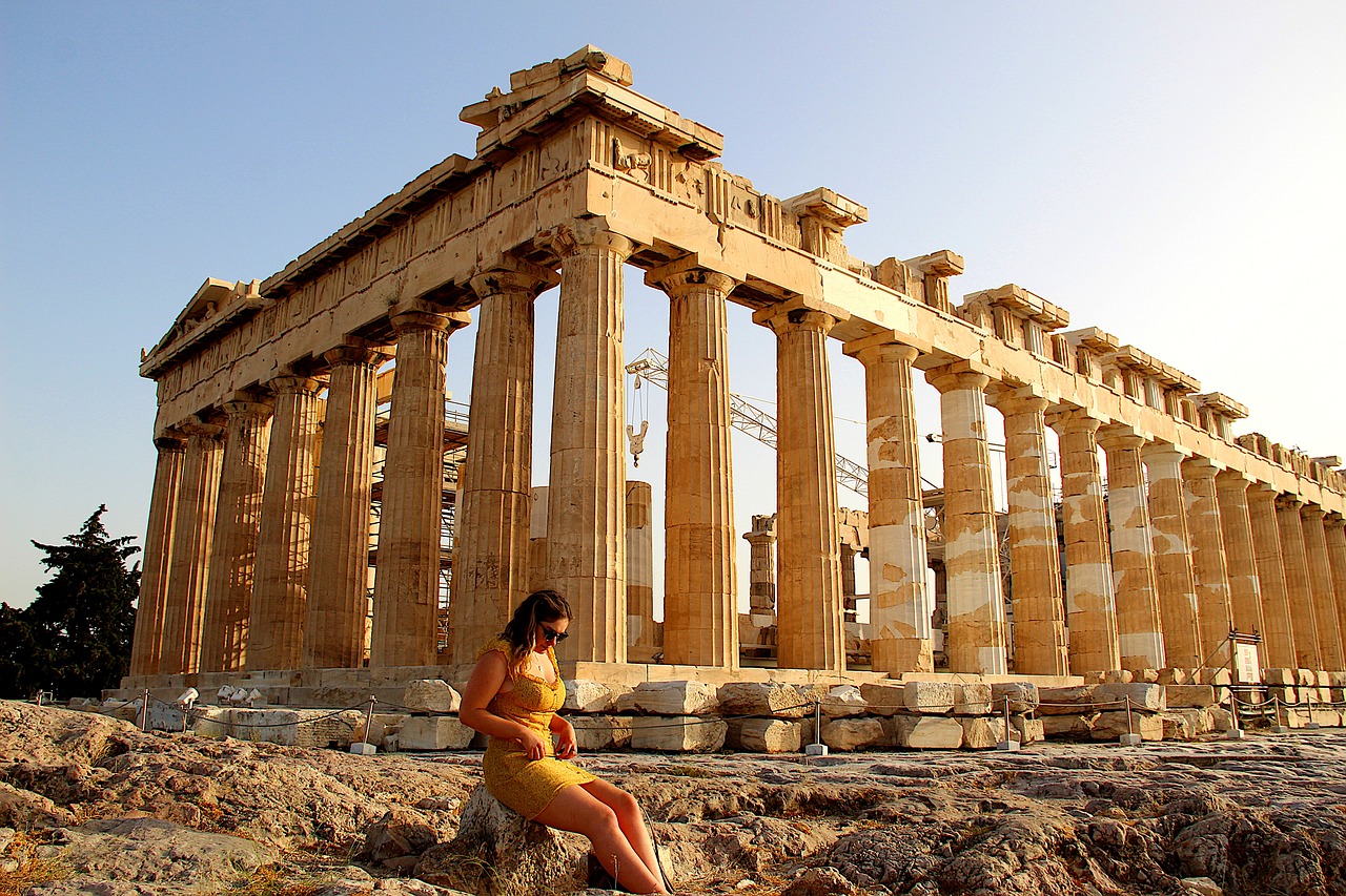 a woman sitting on a rock in front of a large building