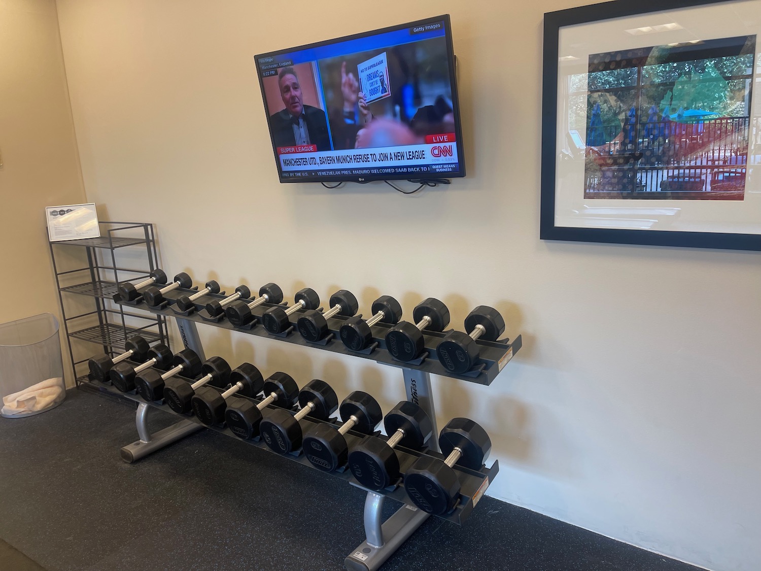 a rack of dumbbells on a wall with a tv on the wall