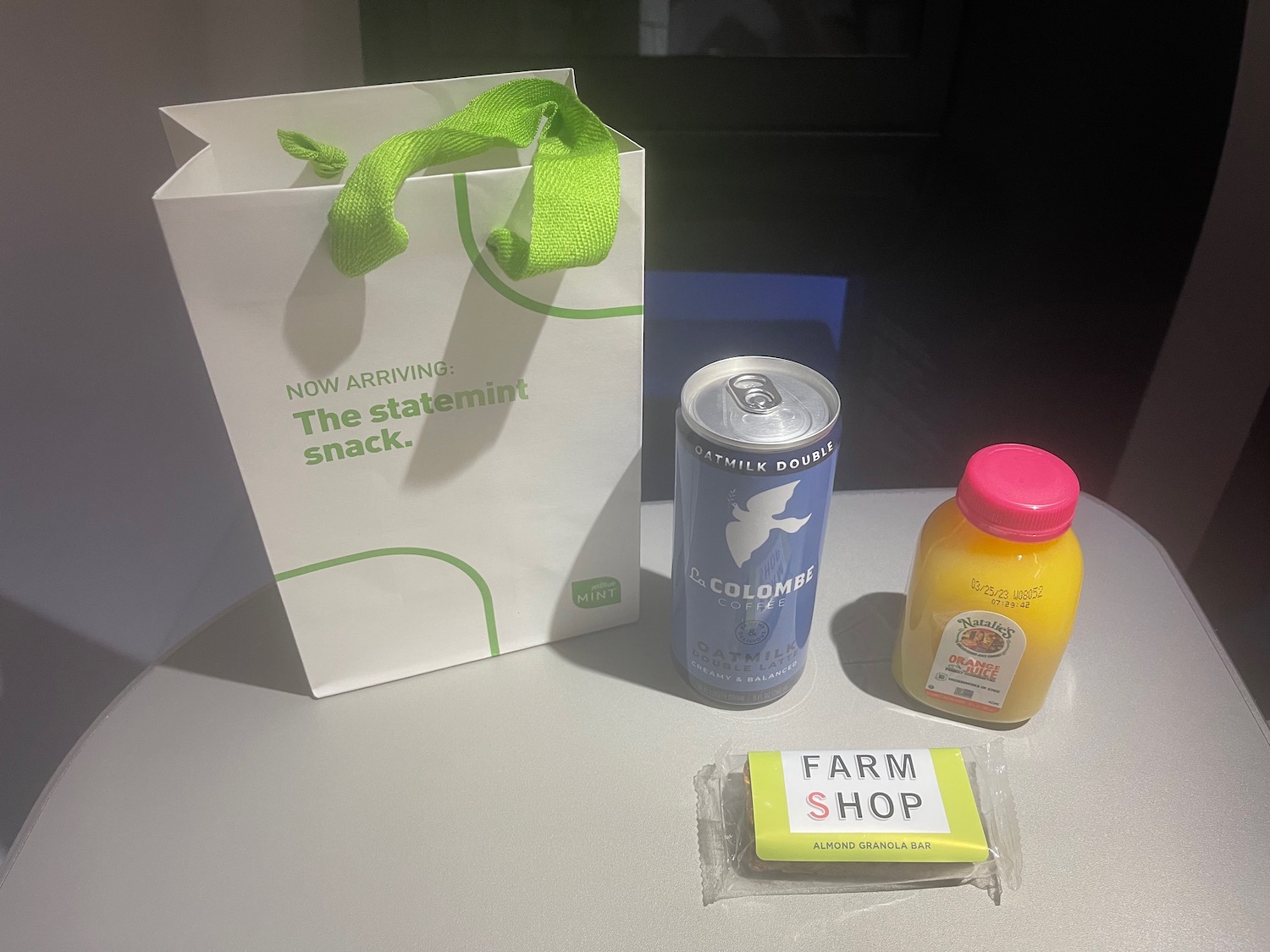 a white bag with a green handle and a can of juice and a package