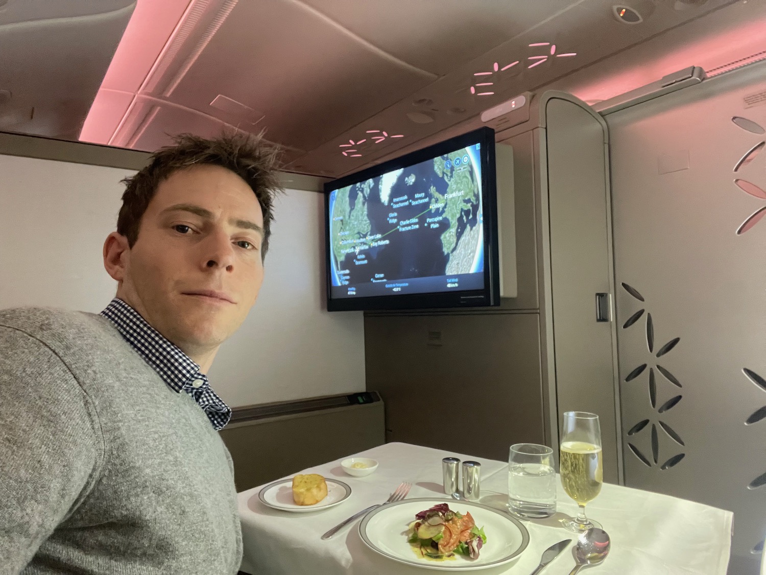 a man sitting at a table with food and a television