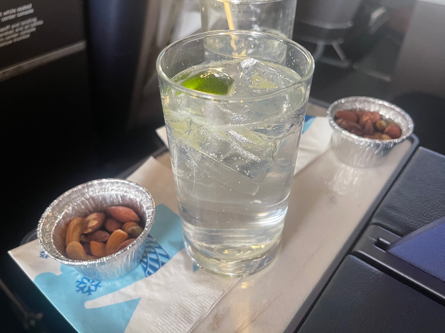 a glass of water with ice and lime in a small tin container