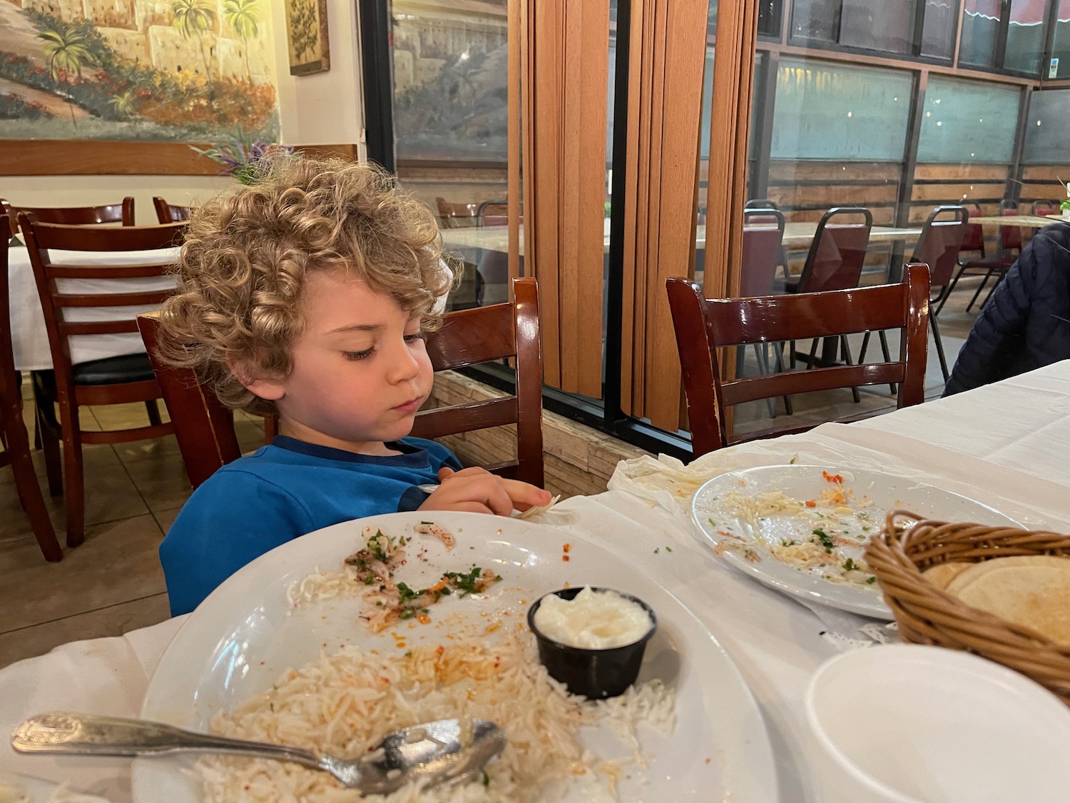 a boy sitting at a table with food on it