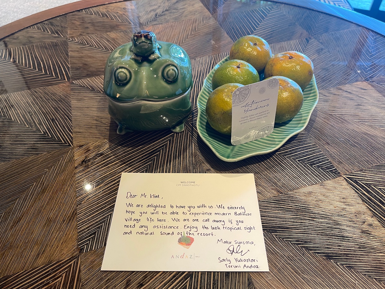 a plate of oranges and a ceramic frog on a table