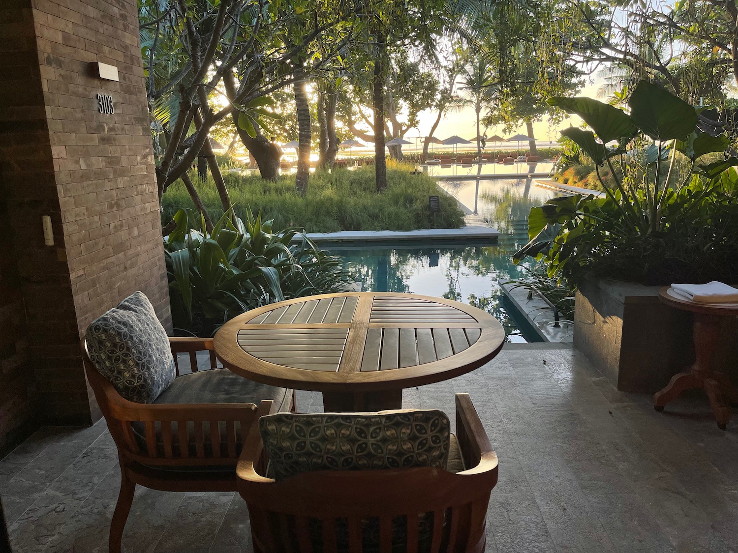 a table and chairs outside with a pool in the background