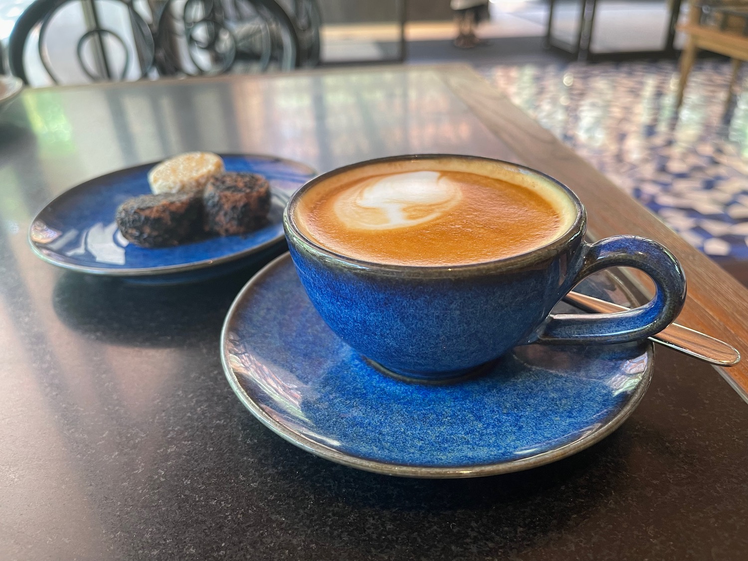 a blue cup of coffee and a plate of brown rocks