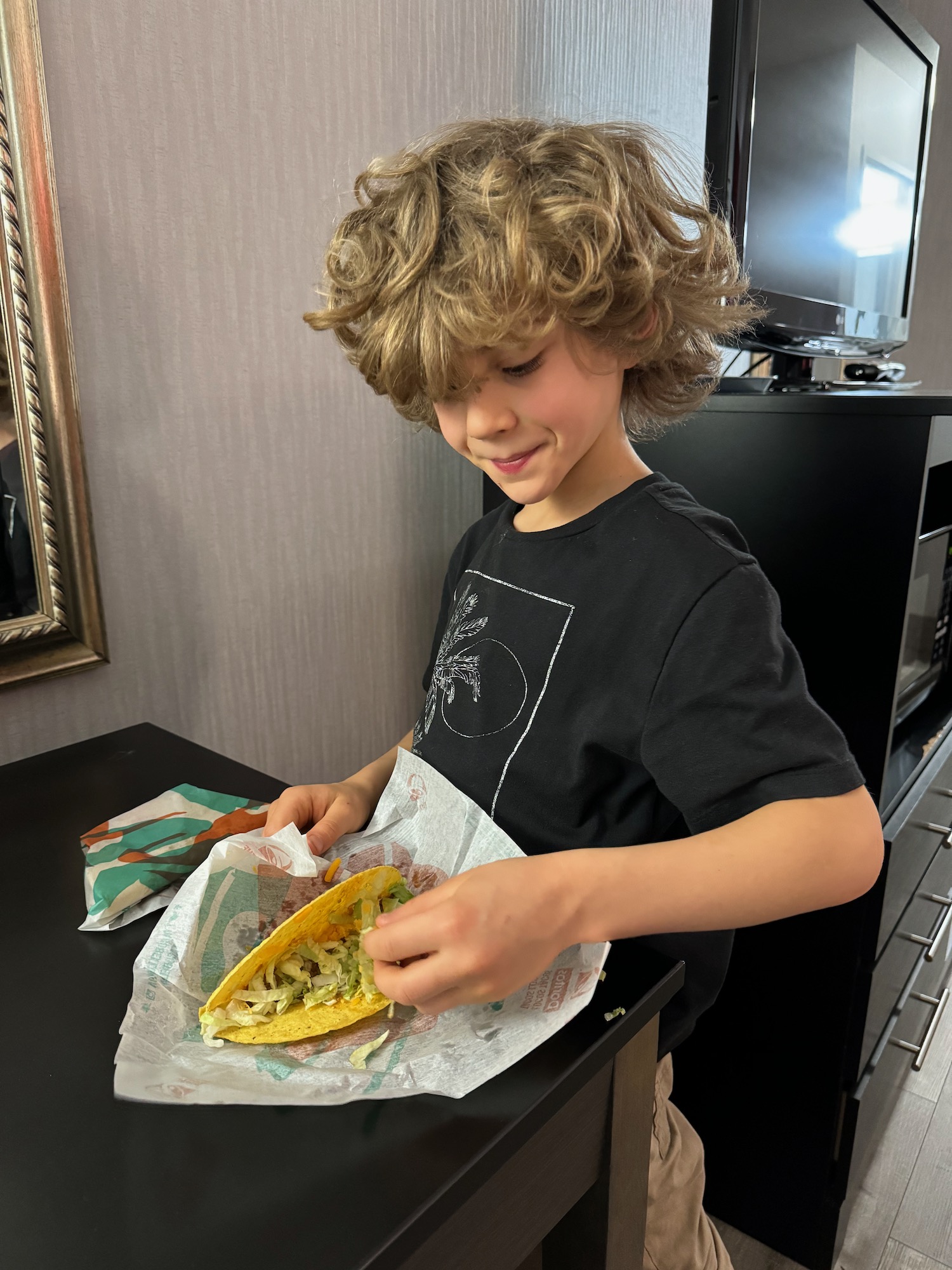 a boy eating taco on a table