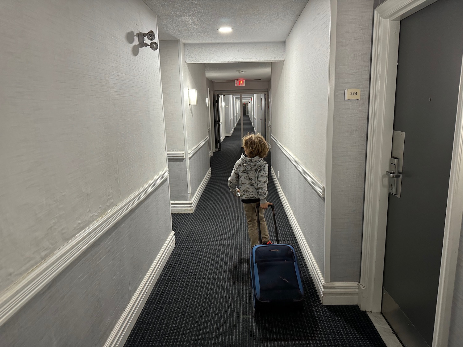 a child with a suitcase in a hallway