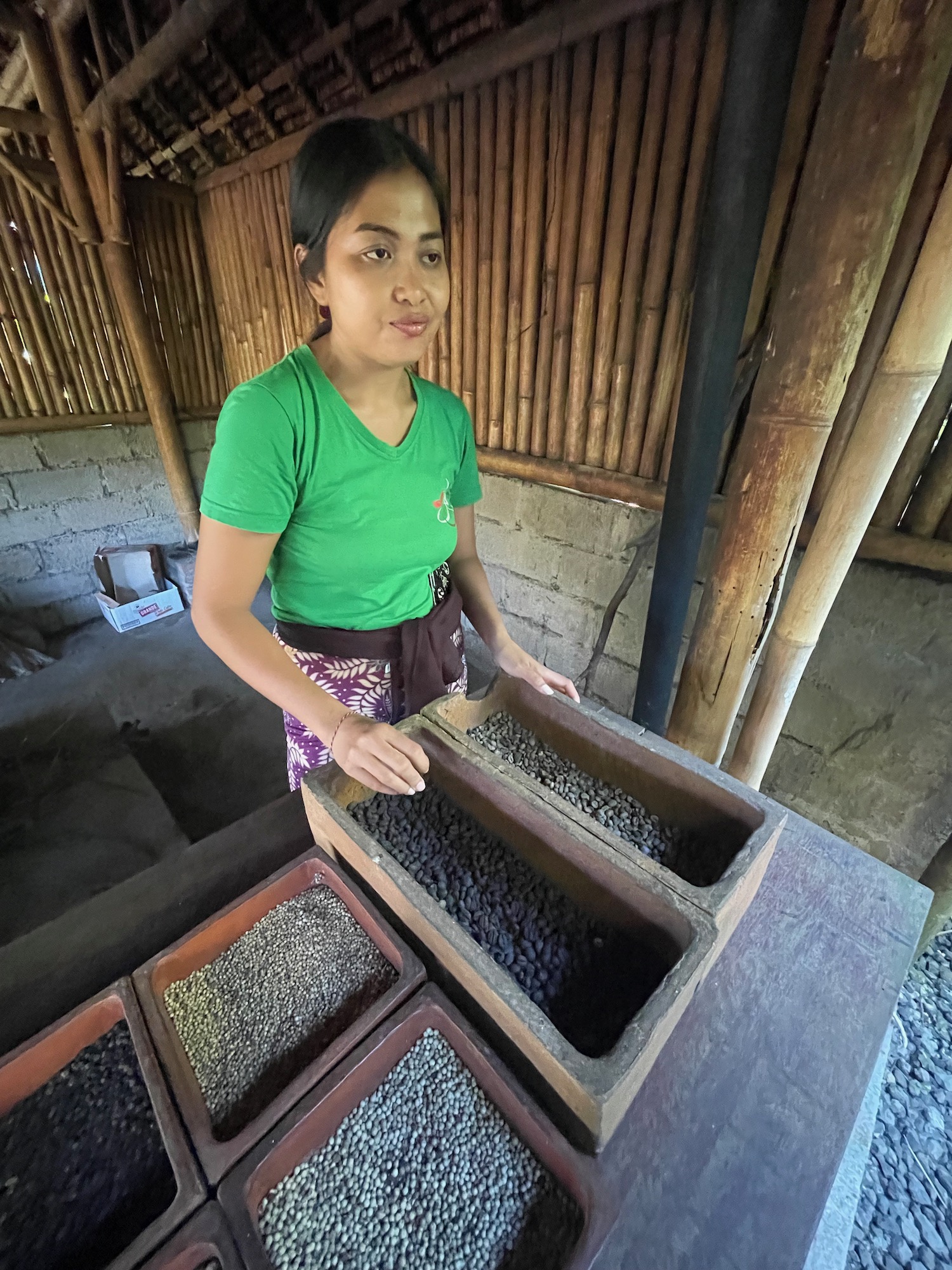 a woman standing next to a wooden container with black grains