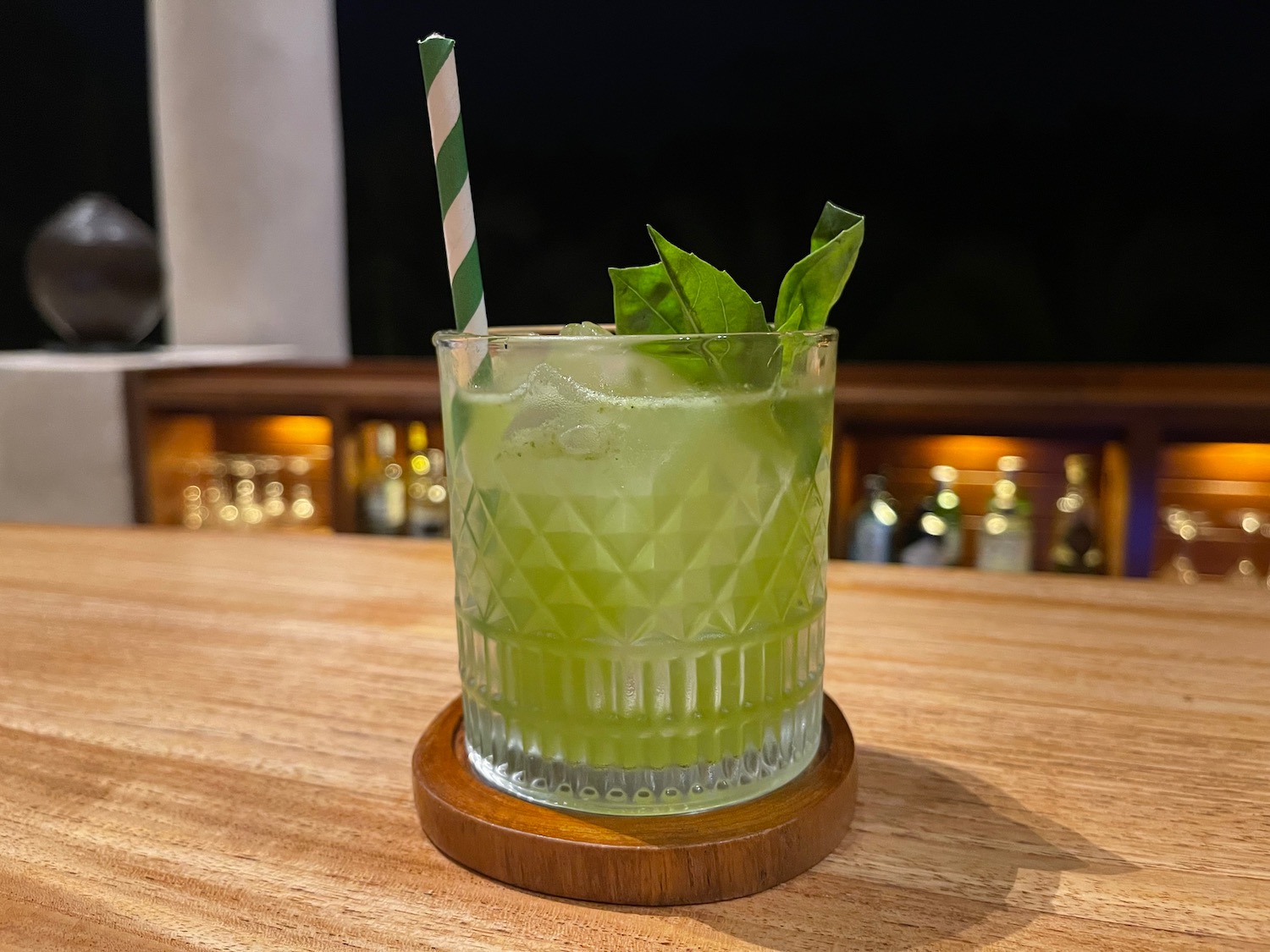 a glass with a drink and a straw on a wood coaster