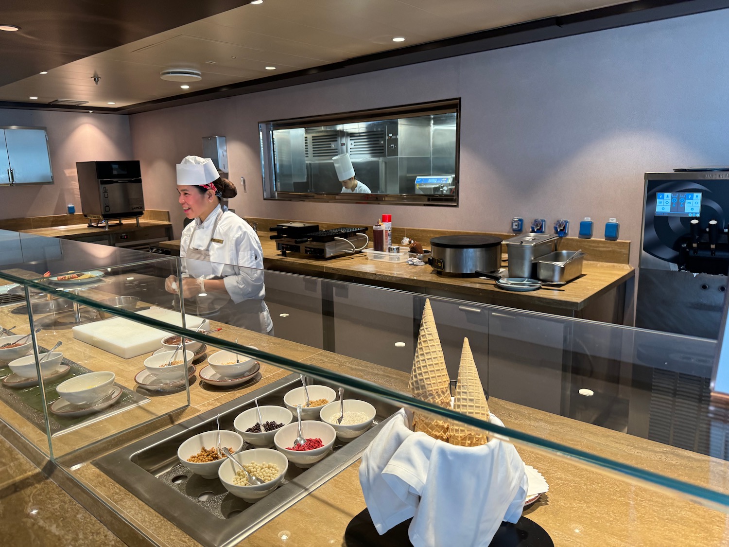 a woman in a chef's uniform behind a glass display case