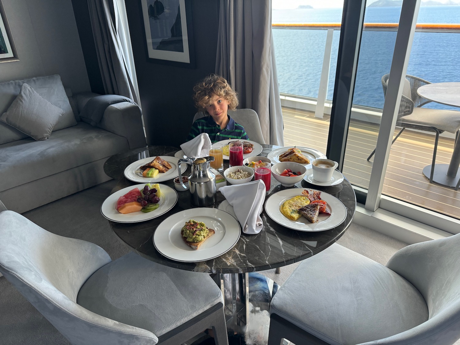 a boy sitting at a table with food on it