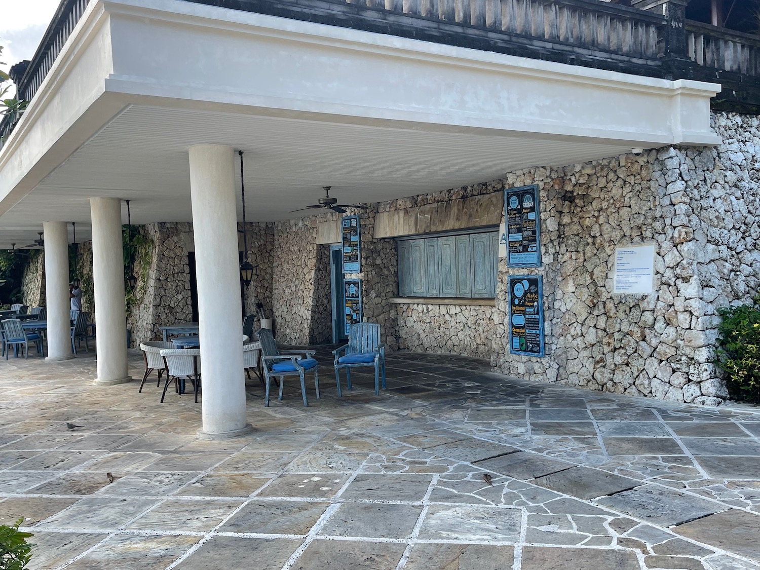 a stone building with a stone wall and chairs