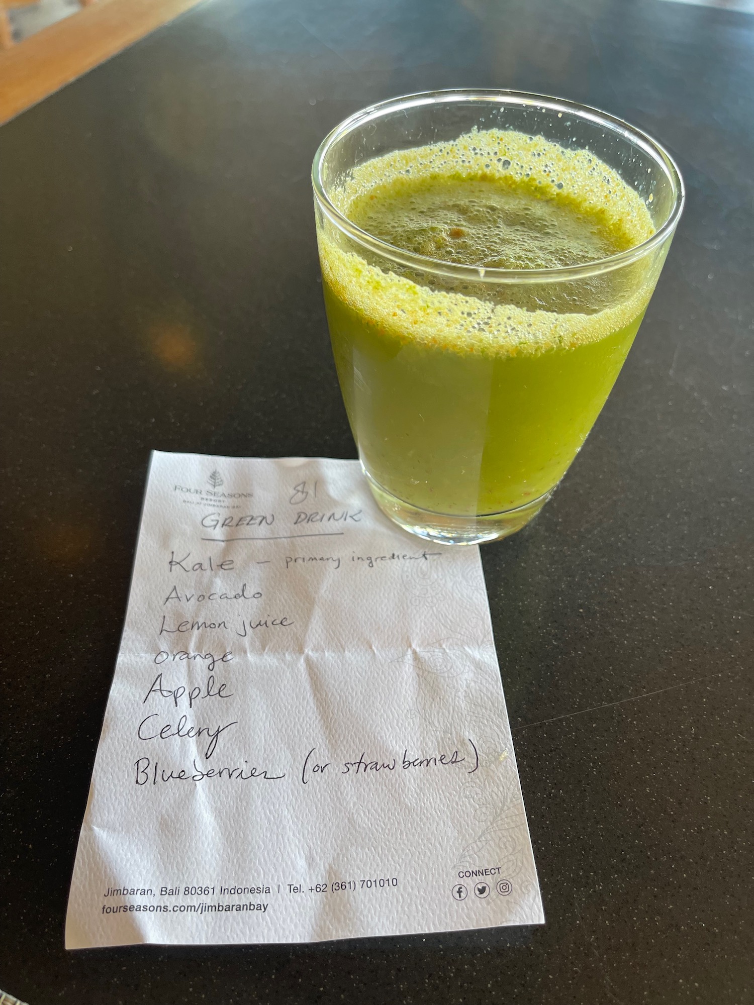 a glass of green juice on a table