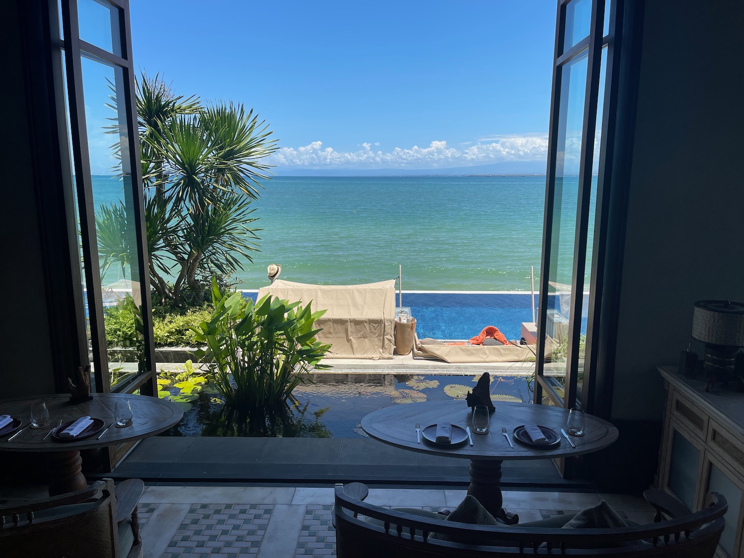 a view of the ocean from a room with a table and chairs