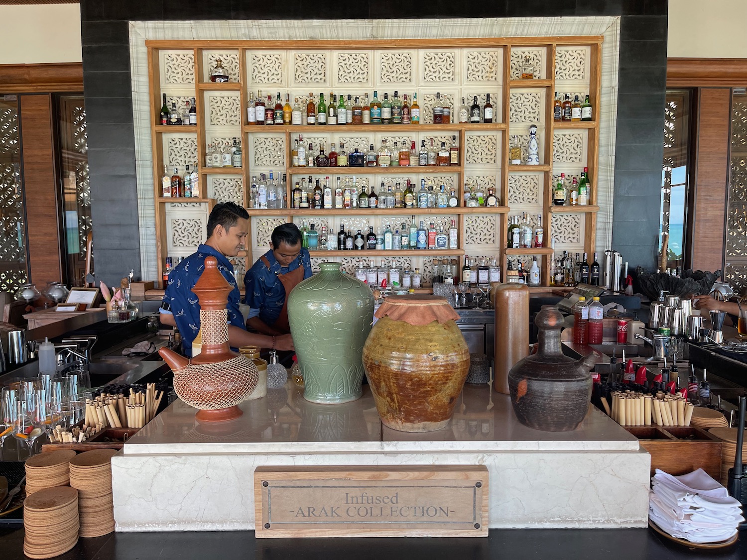 a group of men standing behind a counter with a bar and bottles