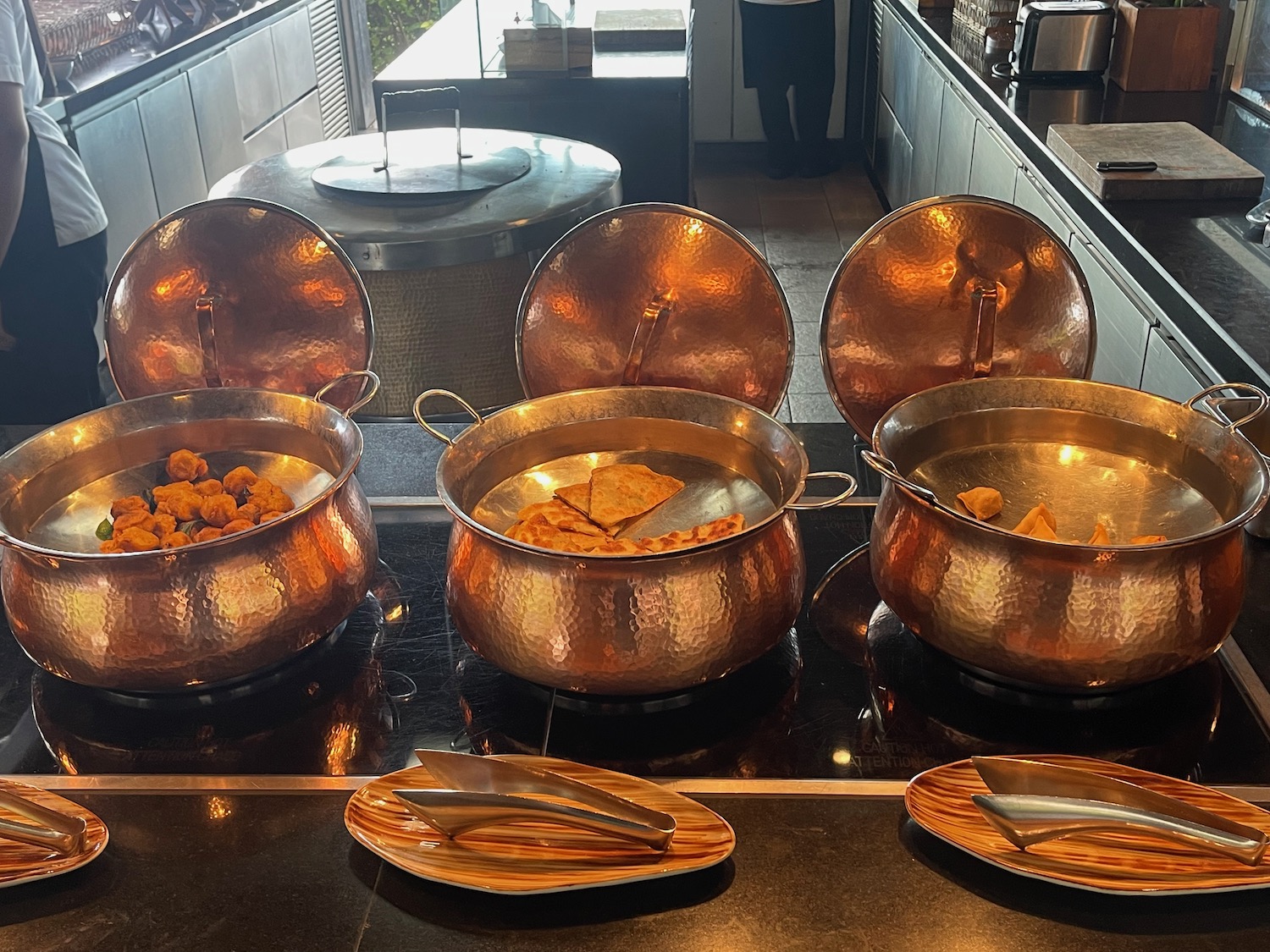 a group of copper pots with food in them