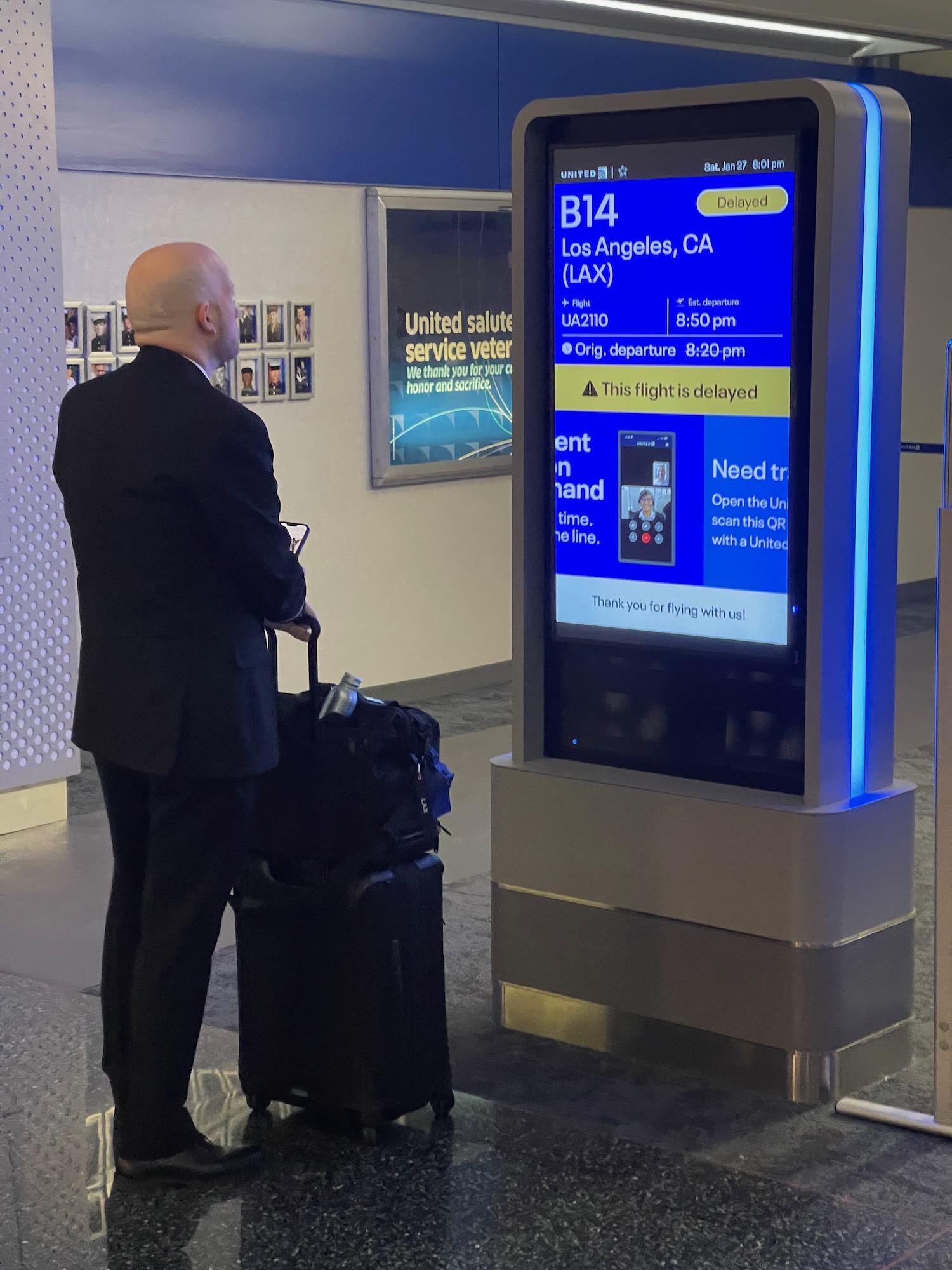 a man in a suit with luggage in front of a digital display