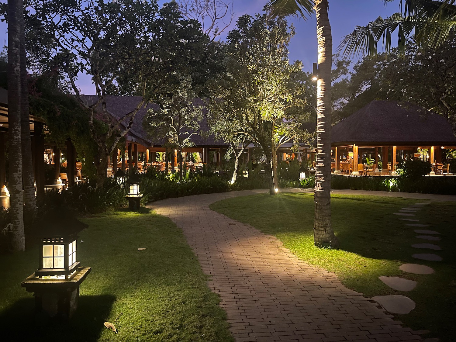 a walkway with lights and trees in the back