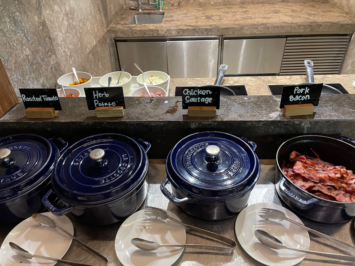a buffet line of blue pots and plates with food on the counter