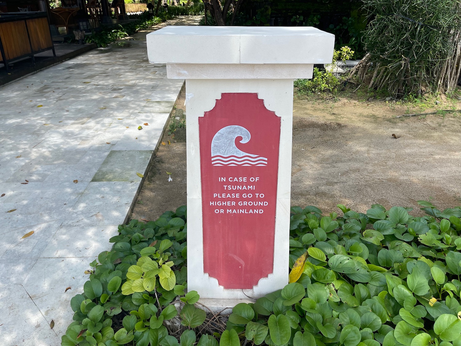 a white and red sign on a stone pillar