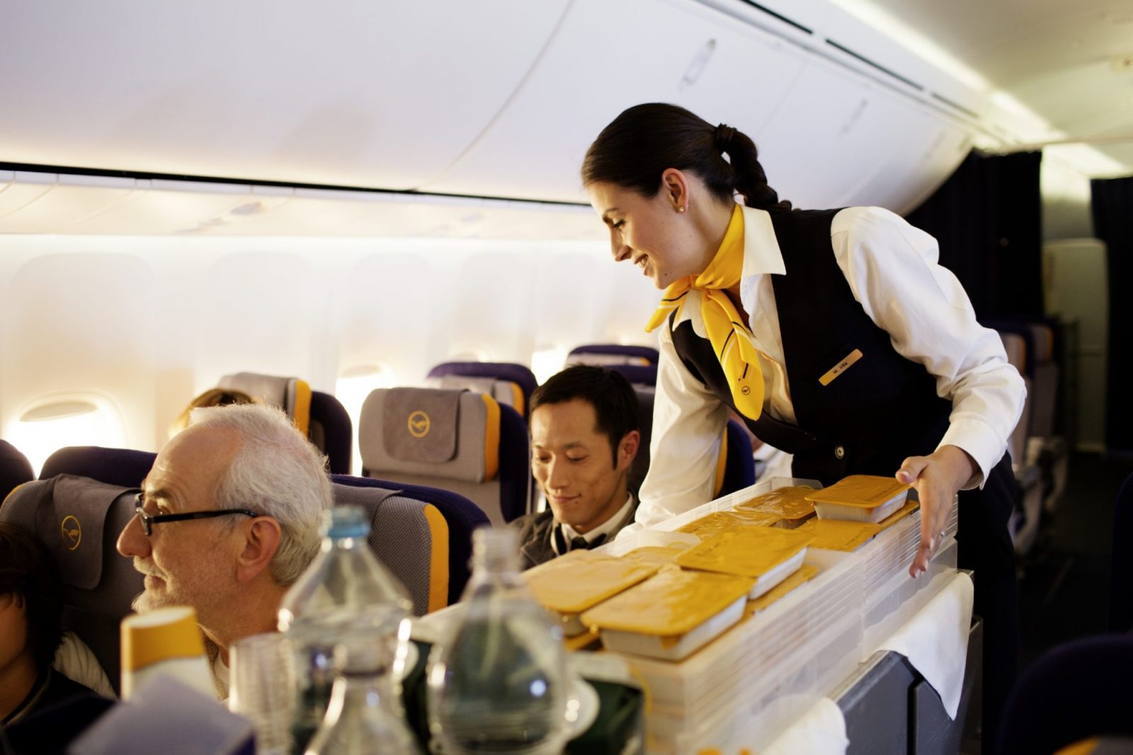 a flight attendant serving people on an airplane