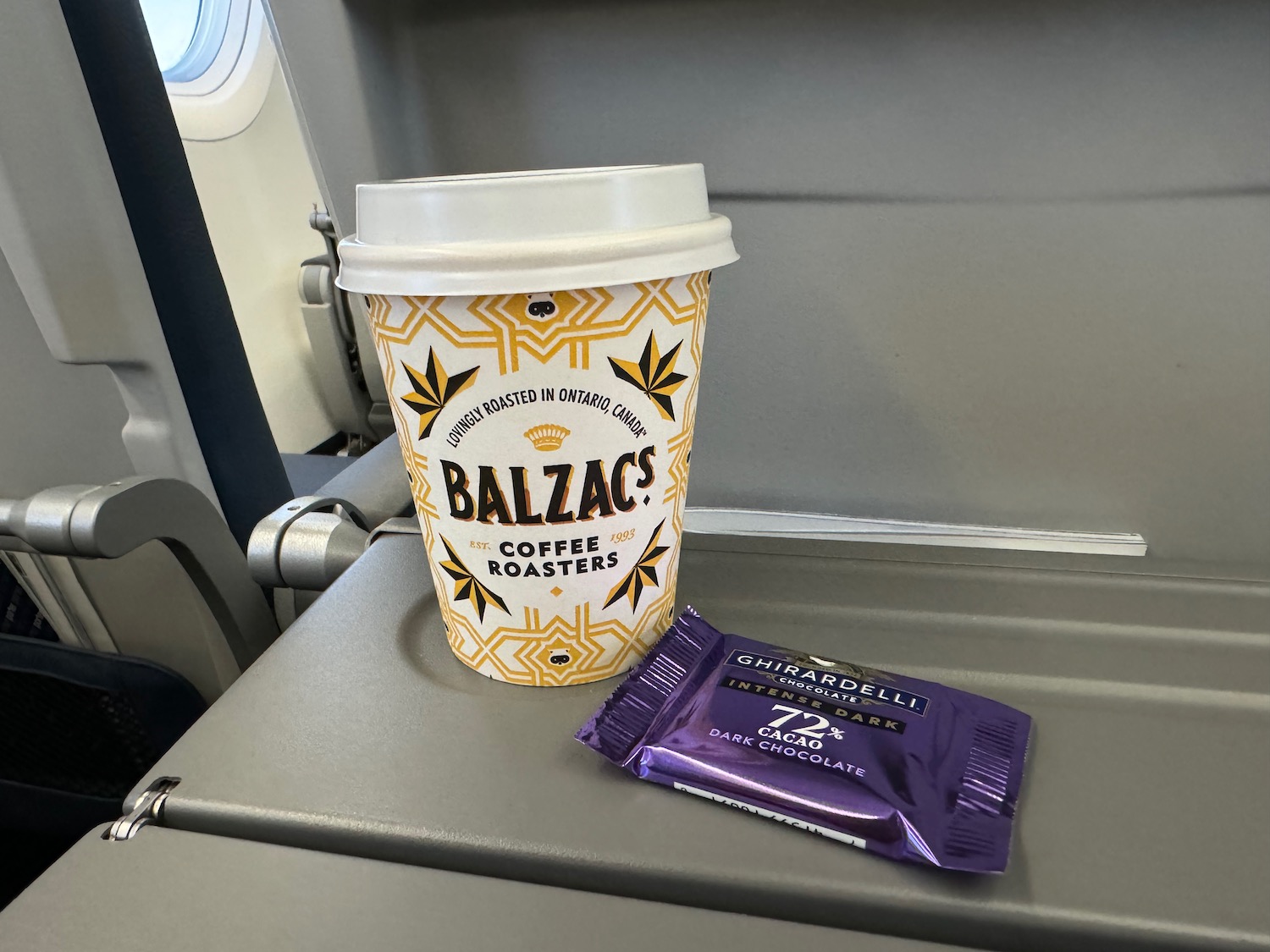 a coffee cup and a packet of candy on a plane
