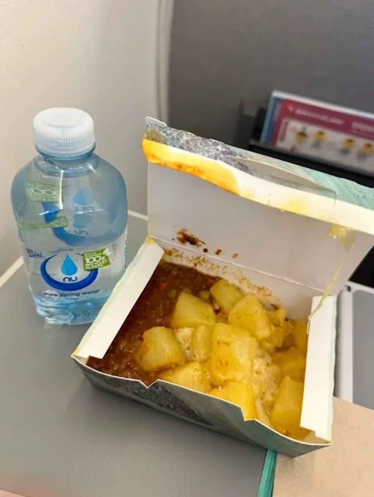 a food in a box next to a bottle of water