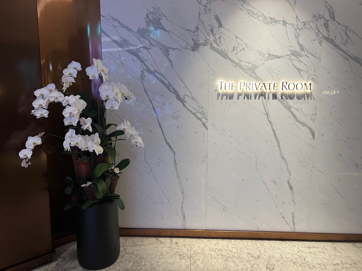 a white flowers in a vase next to a marble wall