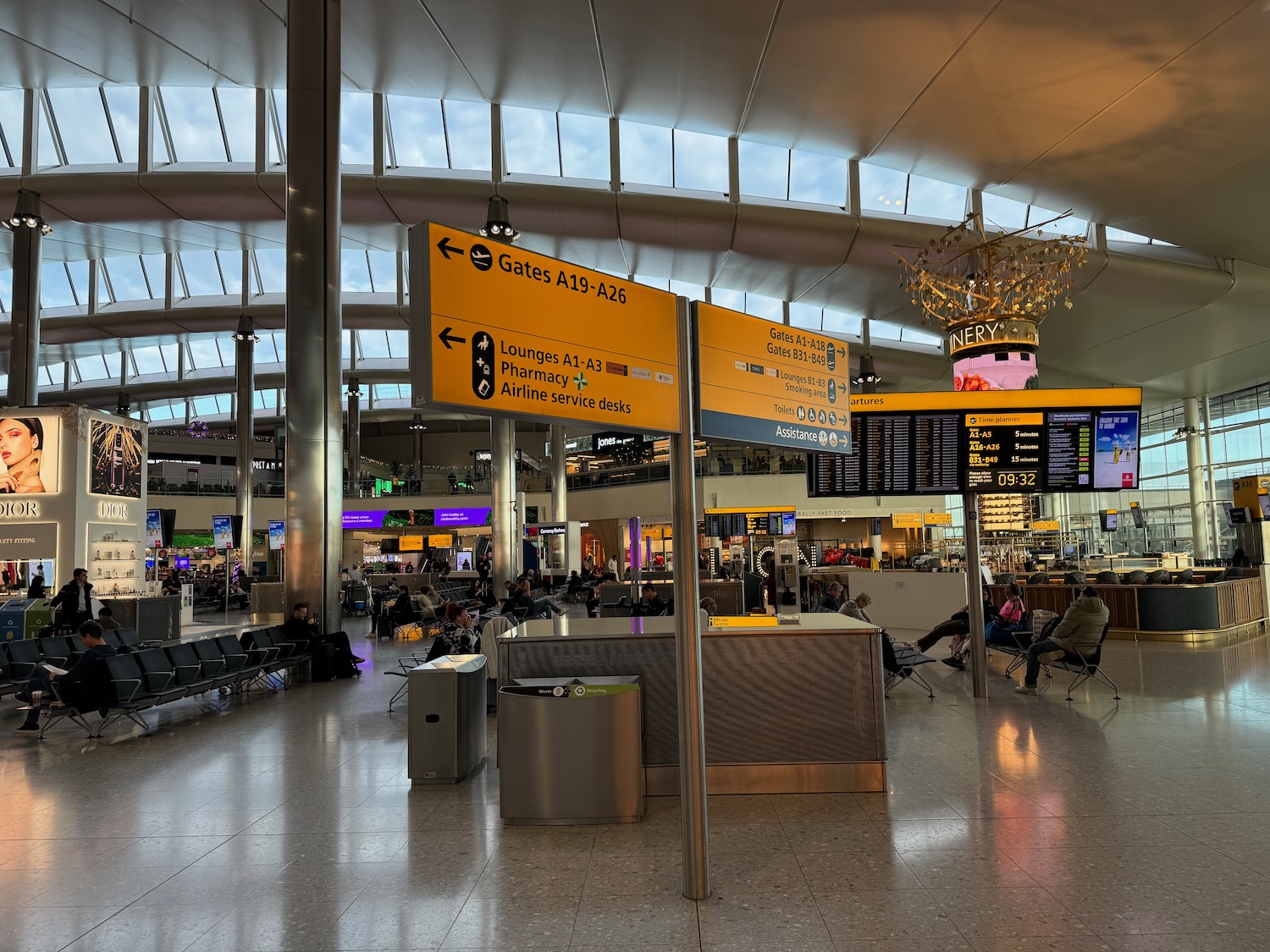 a large airport terminal with signs and people sitting in chairs