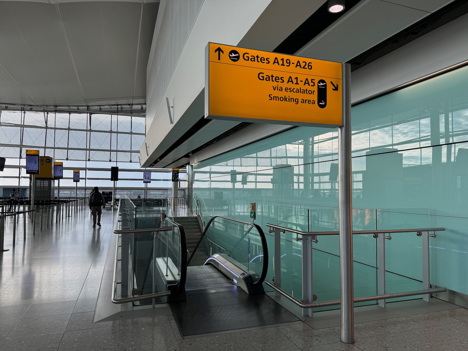 an airport with an escalator and a sign