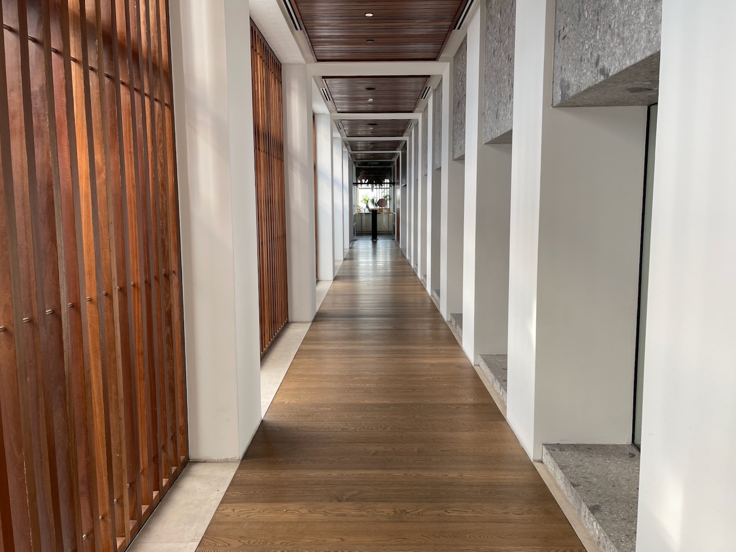 a long hallway with white pillars and wood floor