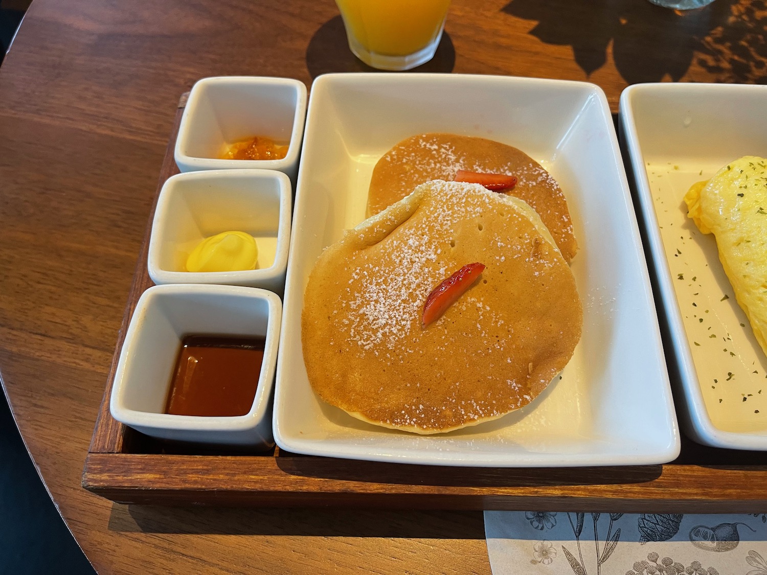 a plate of pancakes with sauces and a glass of juice