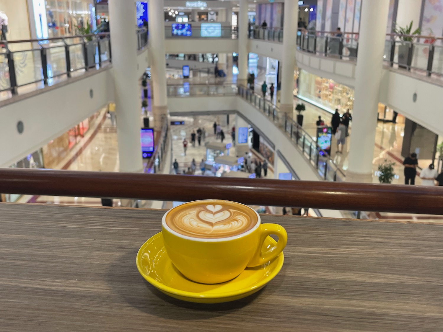 a yellow cup of coffee on a table in a mall