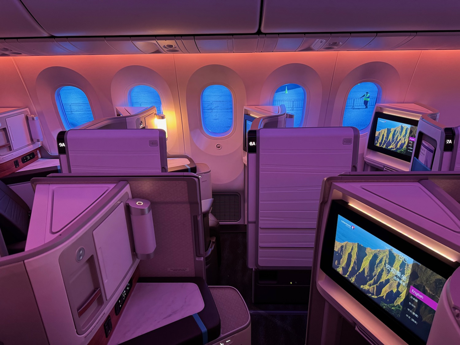 a row of seats with monitors and windows in an airplane