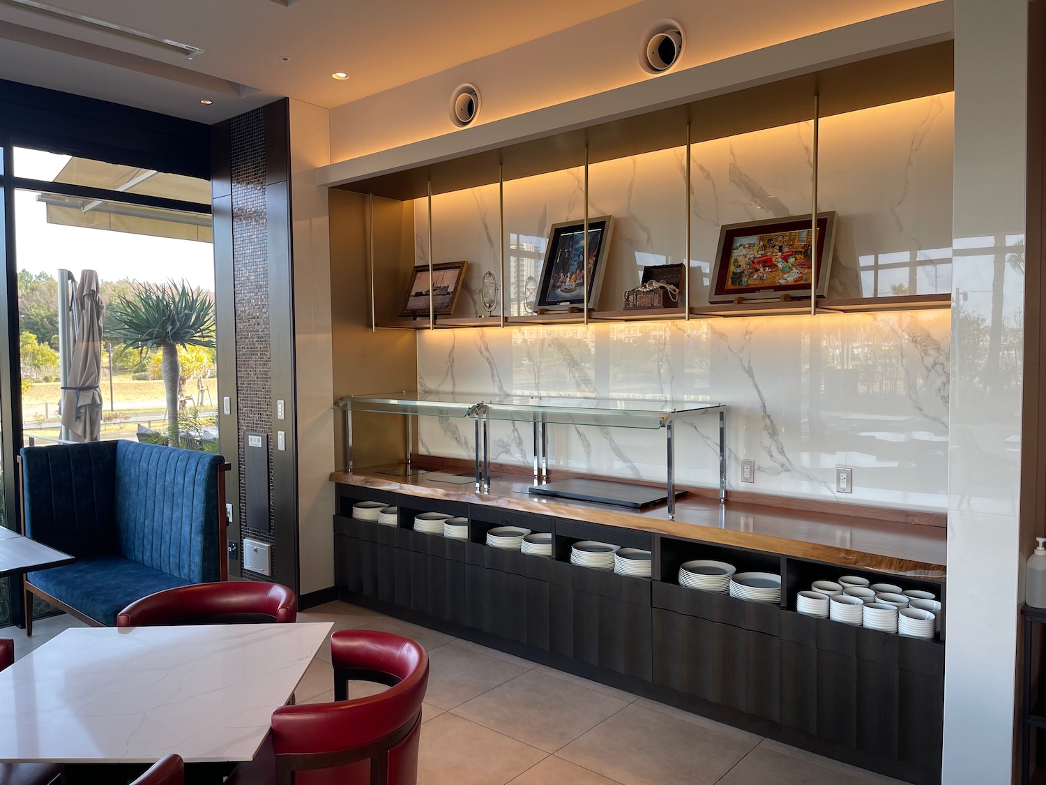 a room with a table and chairs and a glass shelf with plates