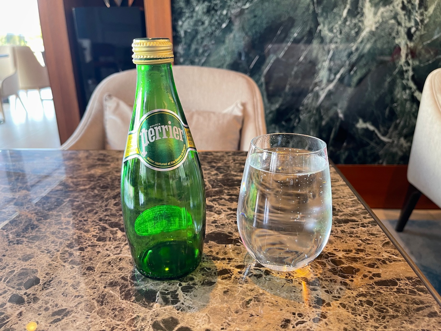 a bottle and a glass of water on a marble table