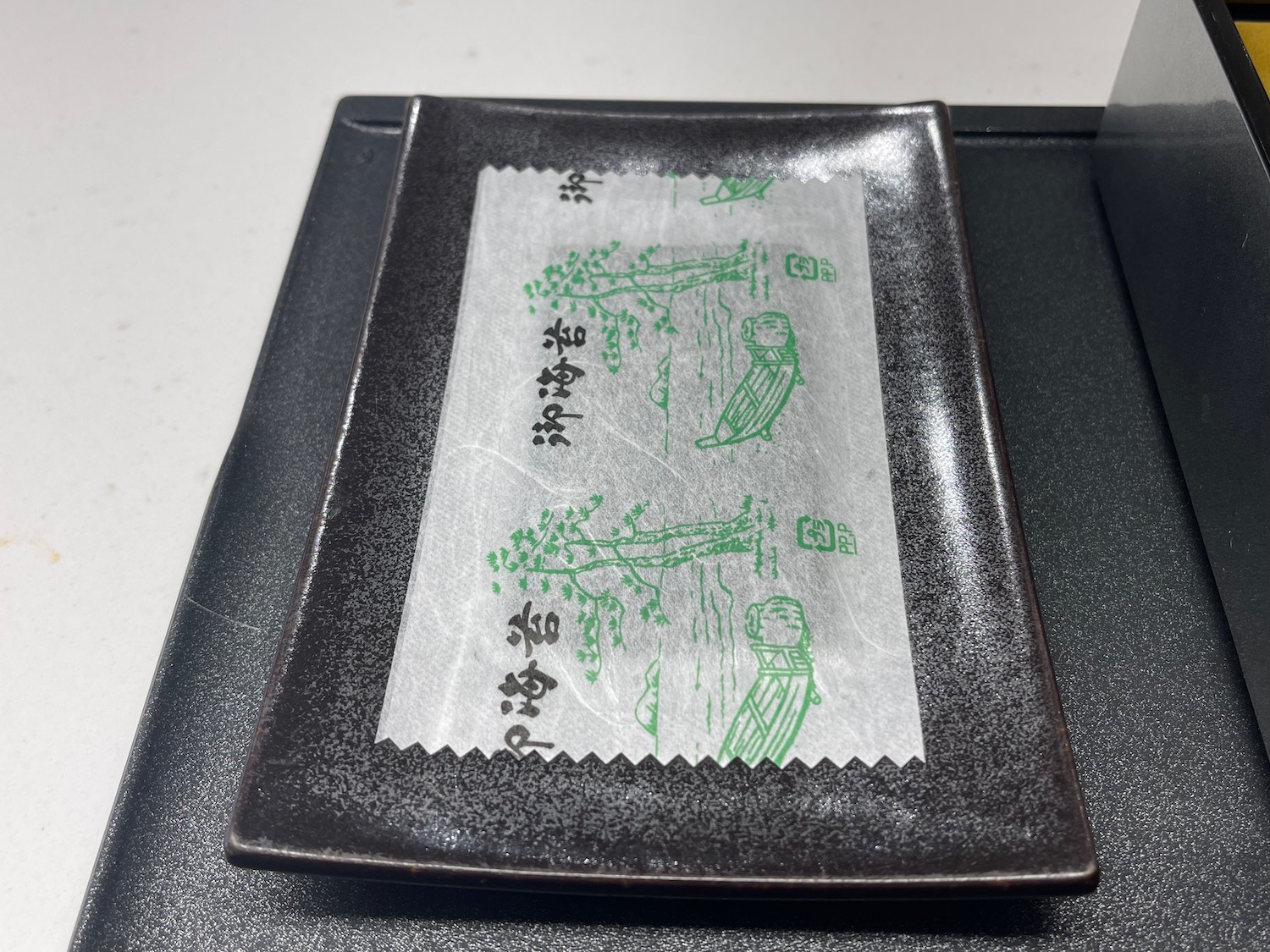 a rectangular black plate with a white and green wrapper on it