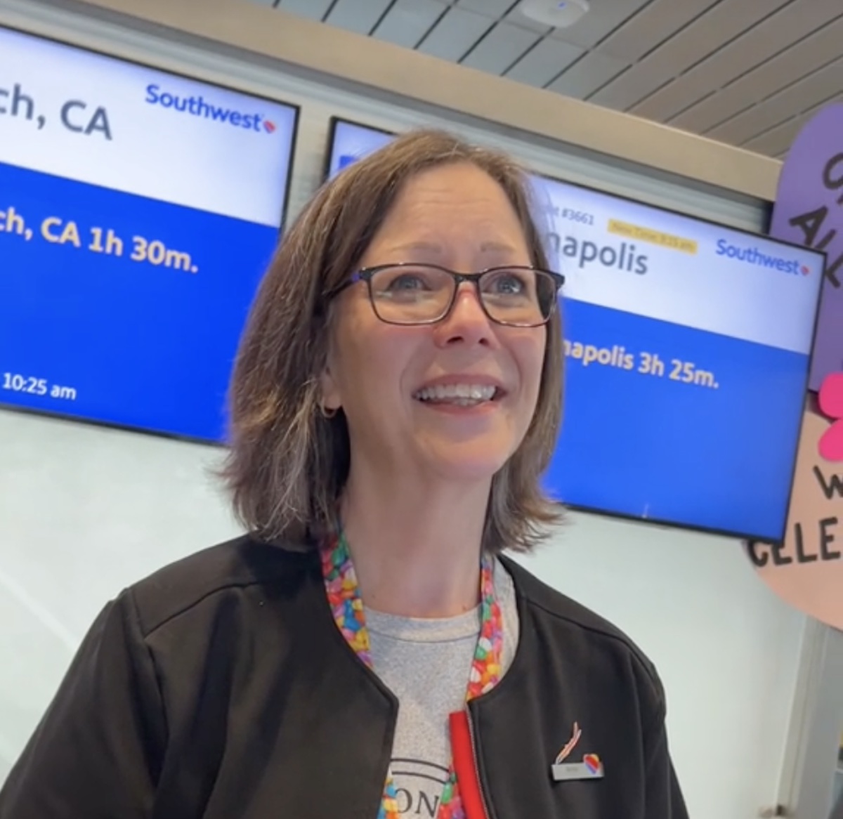 a woman smiling in front of a sign