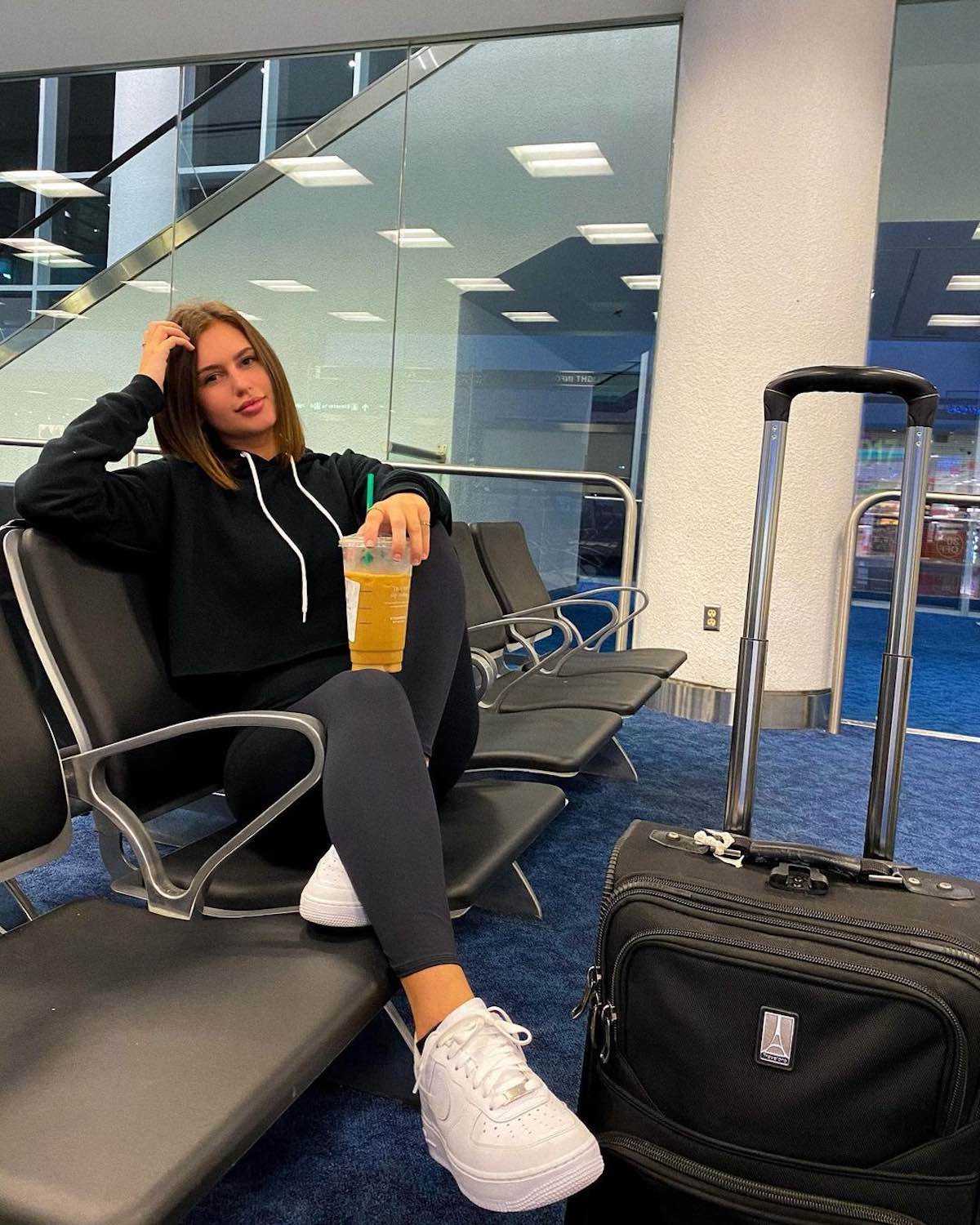 a woman sitting on a chair with a drink and luggage